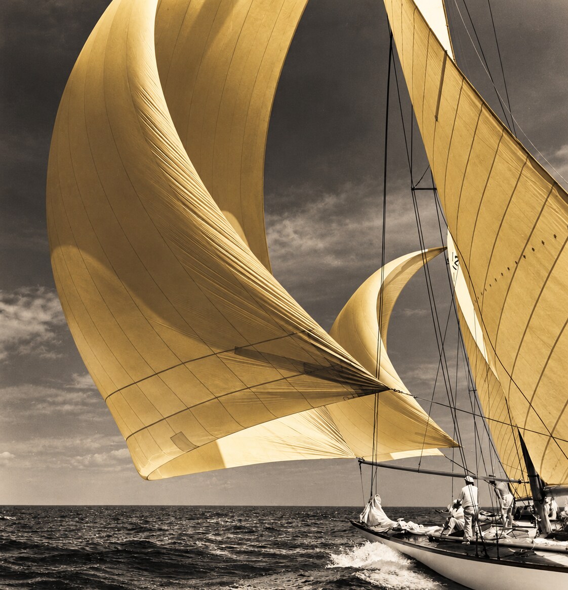 Golden spinnakers filling with wind above a sailing yacht at sea